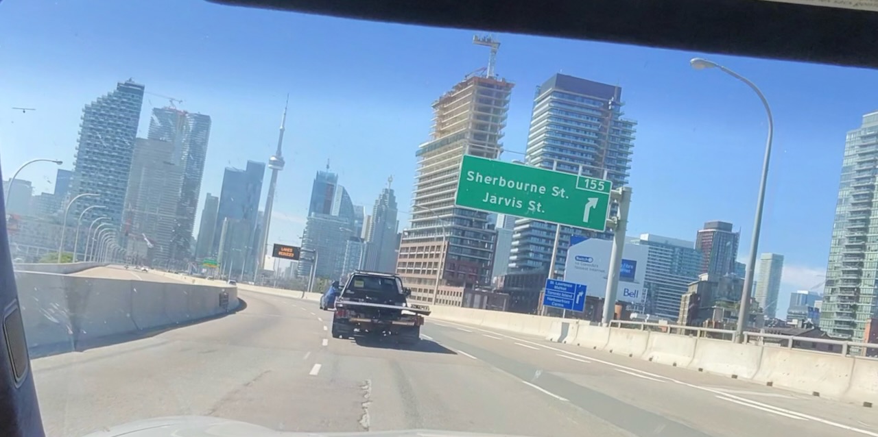 The CN Tower is visible in the distance amongst skyscapers while I drive my way into the city